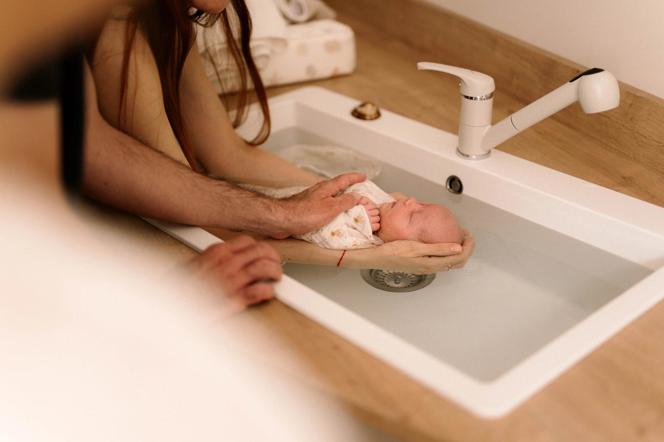 Bain Thérapeutique bébé - bébé dans les bras de maman et papa et accompagné de Charlotte TRAMIER auxiliaire de puériculture et accompagnante parentale. Un réel cadeau pour parents et bébé