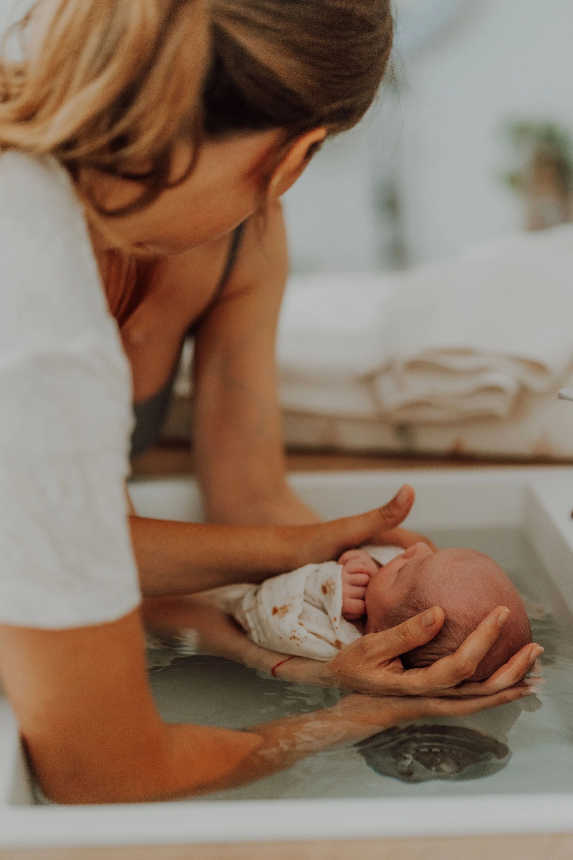 Bain enveloppé bébé dans les bras de ses parents et accompagné par Charlotte TRAMIER auxiliaire de puériculture et accompagnante parentale. Séance de soin et de bien être pour bébé , nouveaux nés et parents. 
